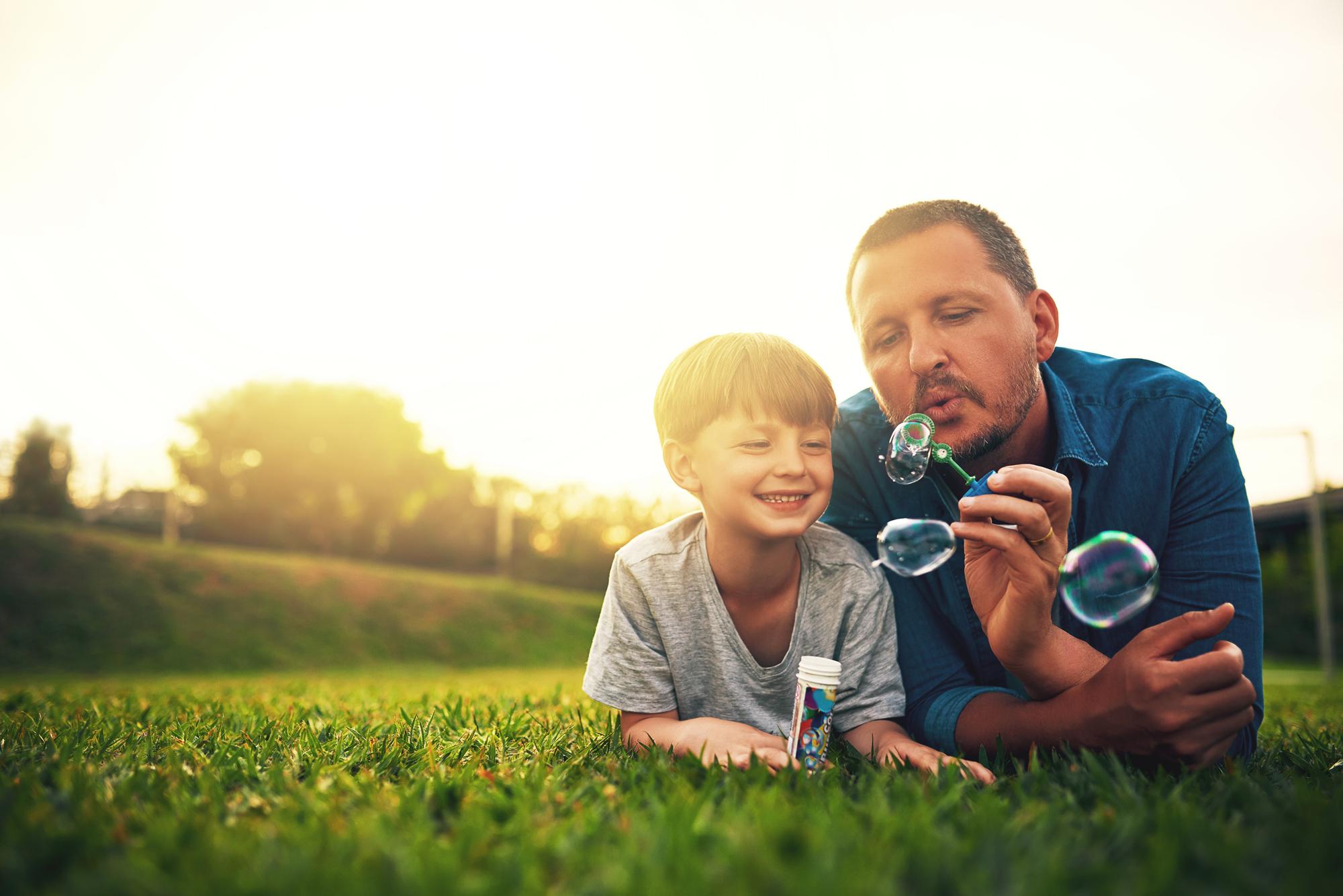 Lawn Care Columbia MO | Dad and Son Blowing Bubbles on the Grass